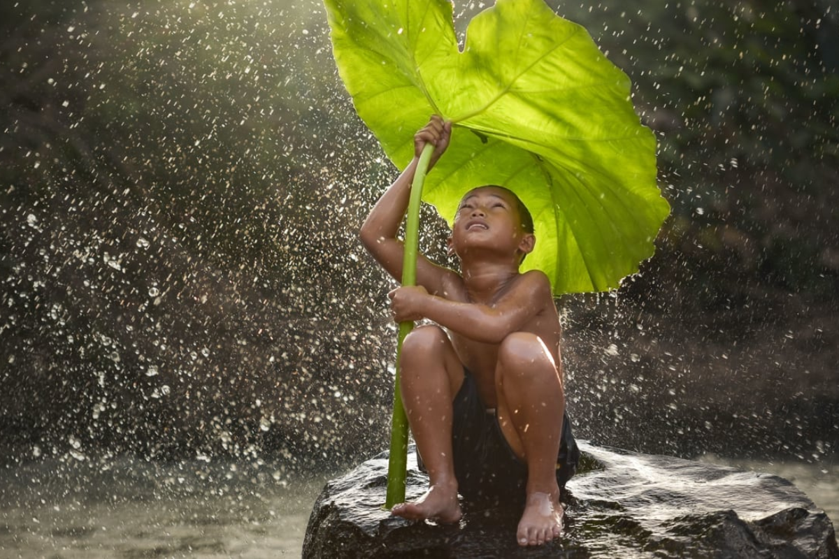 A Laos Boy playing in Rain - World Mate Travel