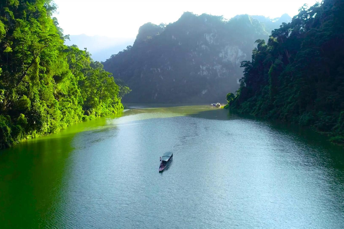 Scenic boat ride on the calm waters of the Gam River, surrounded by limestone cliffs