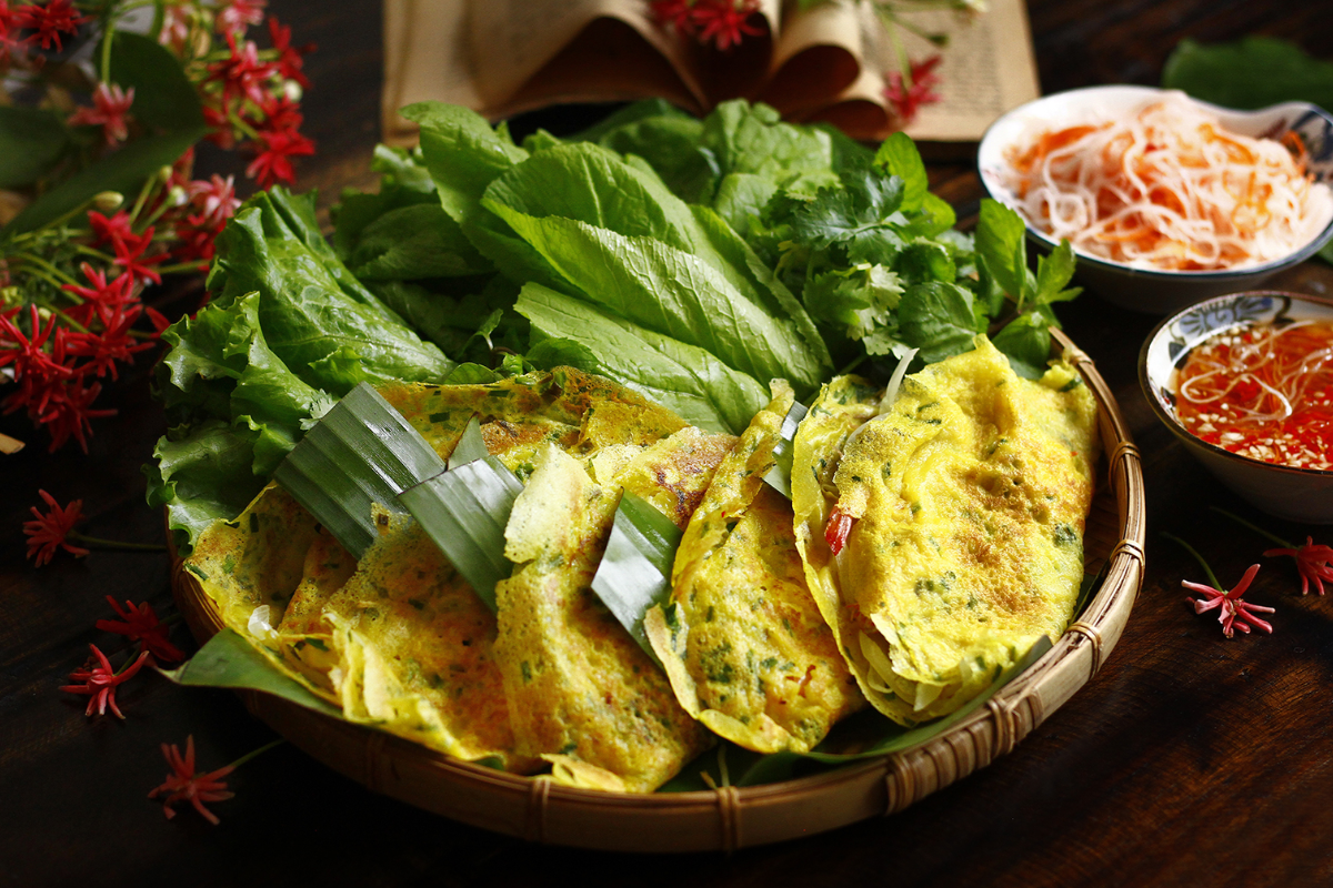 Banh Xeo sizzling on a pan in a Saigon food stall