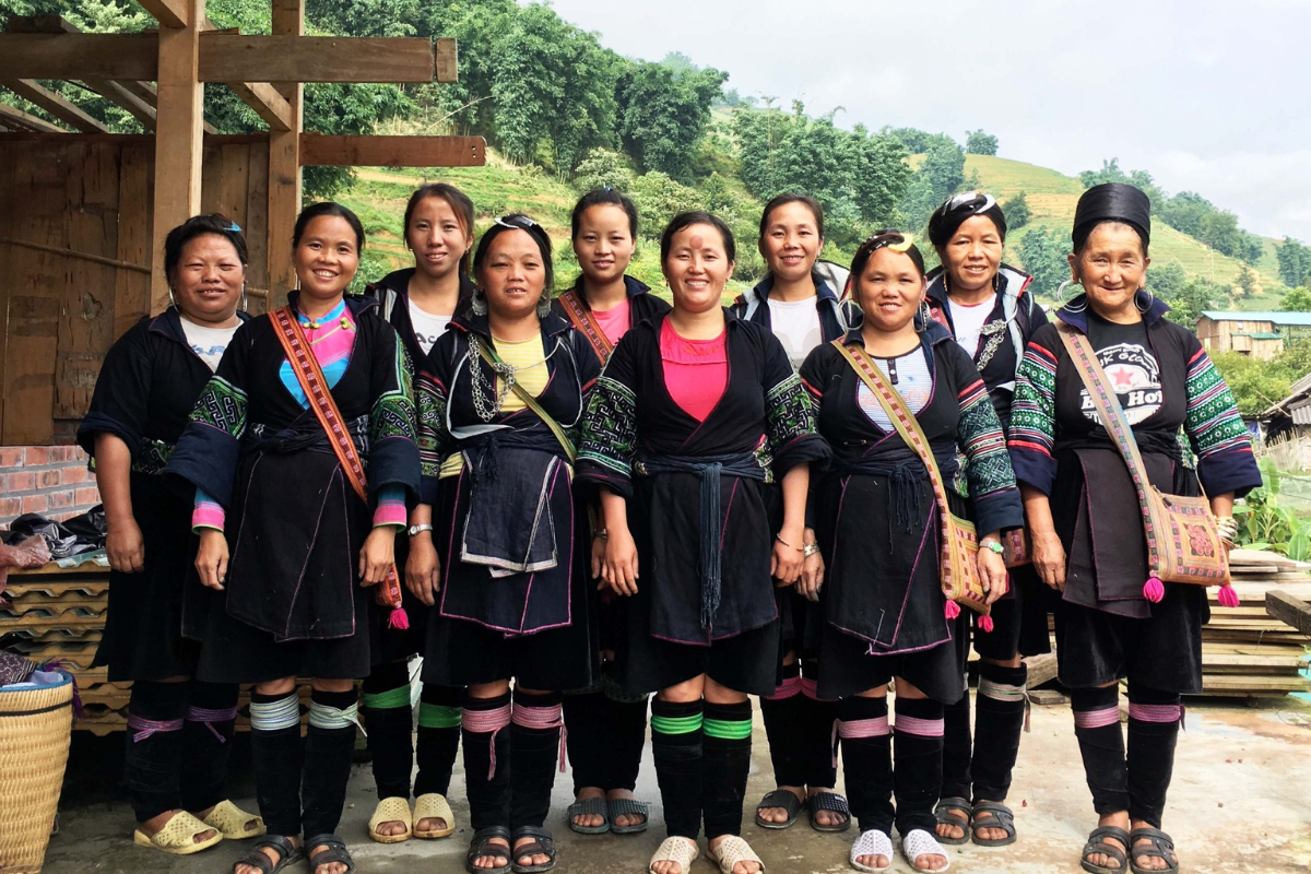 Black H’mong women wearing traditional indigo clothing and carrying baskets in a Sapa village