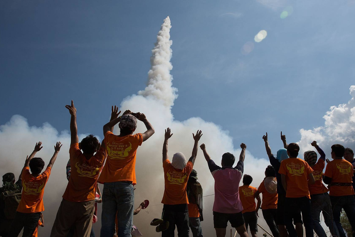 Rocket launching during Bun Bang Fai festival with cheering crowd and traditional costumes