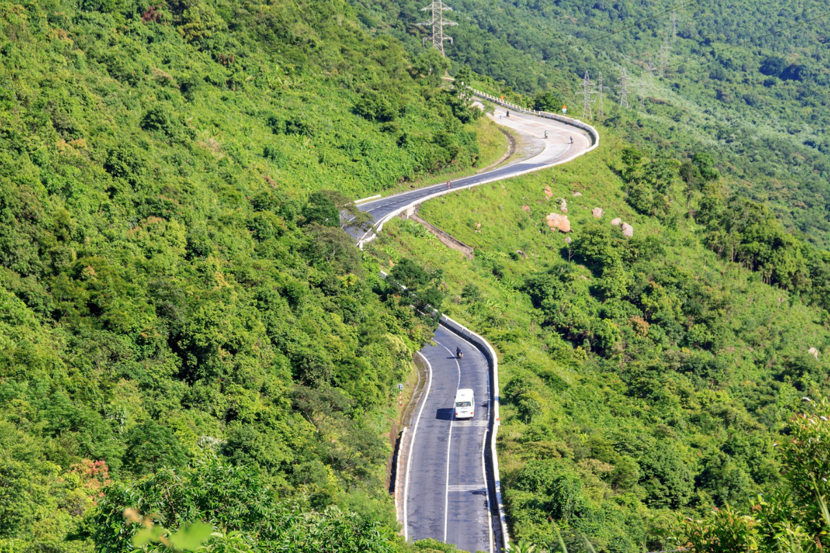 The winding road of Hai Van Pass with mountains and clouds in the background