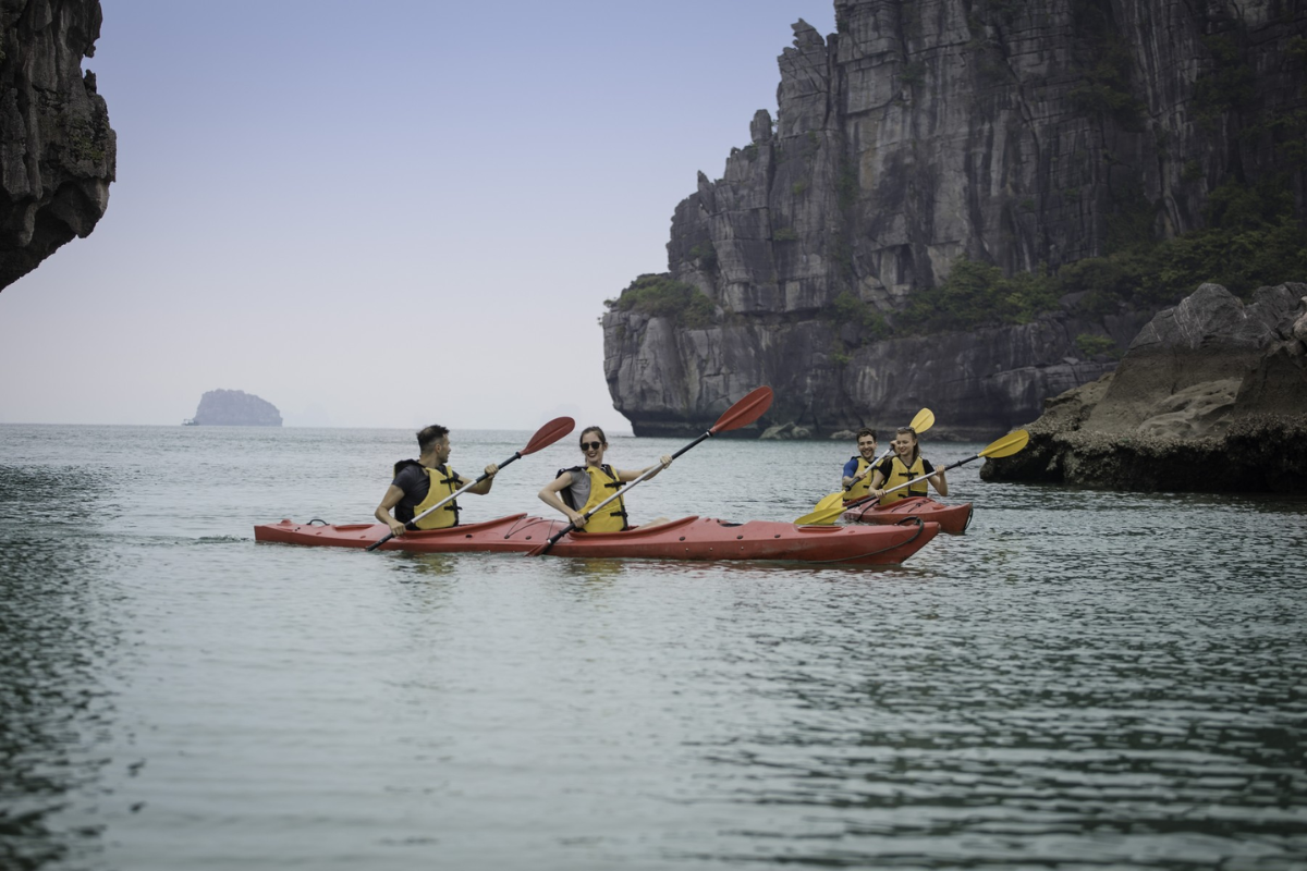 Tourist kayaking through calm waters between limestone cliffs in Ha Long Bay in February