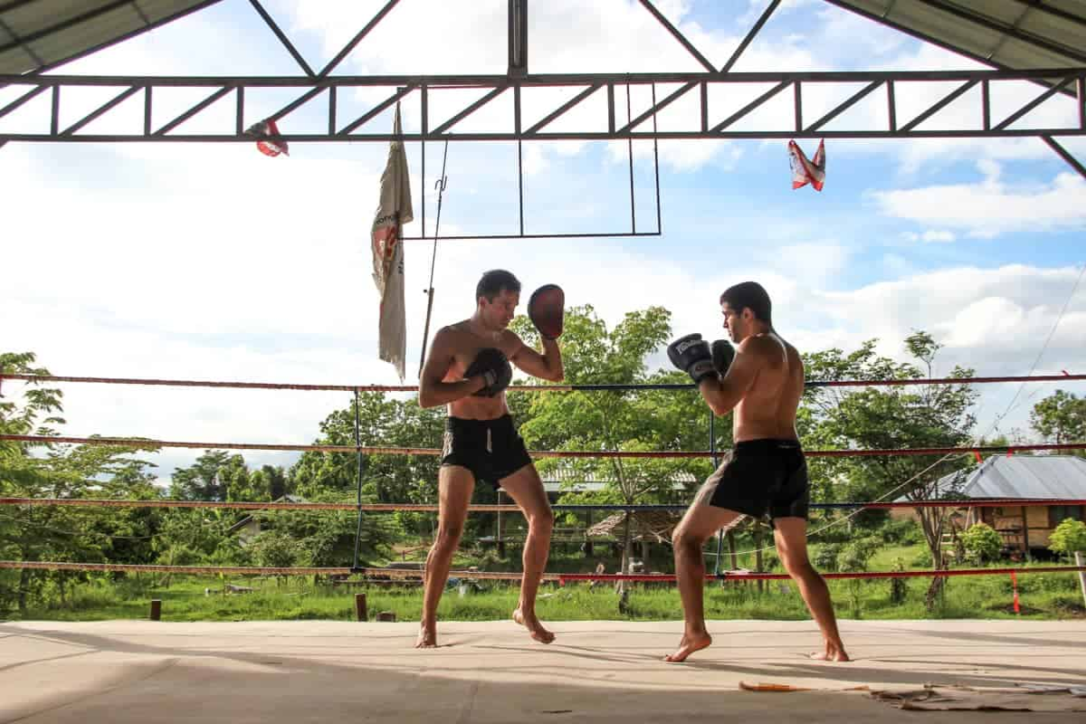 Tourists training in Muay Thai with local instructors at a gym in Thailand