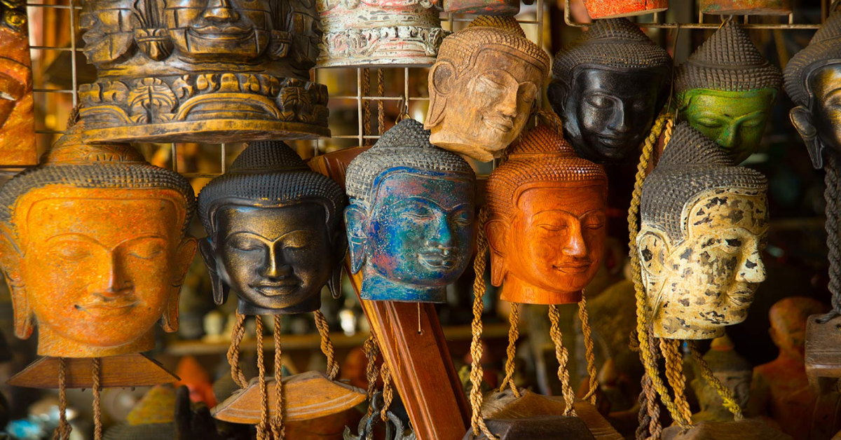 Selection of Cambodian souvenirs on display in a Siem Reap market — silk scarves, kramas, wooden Buddhas, and silverware