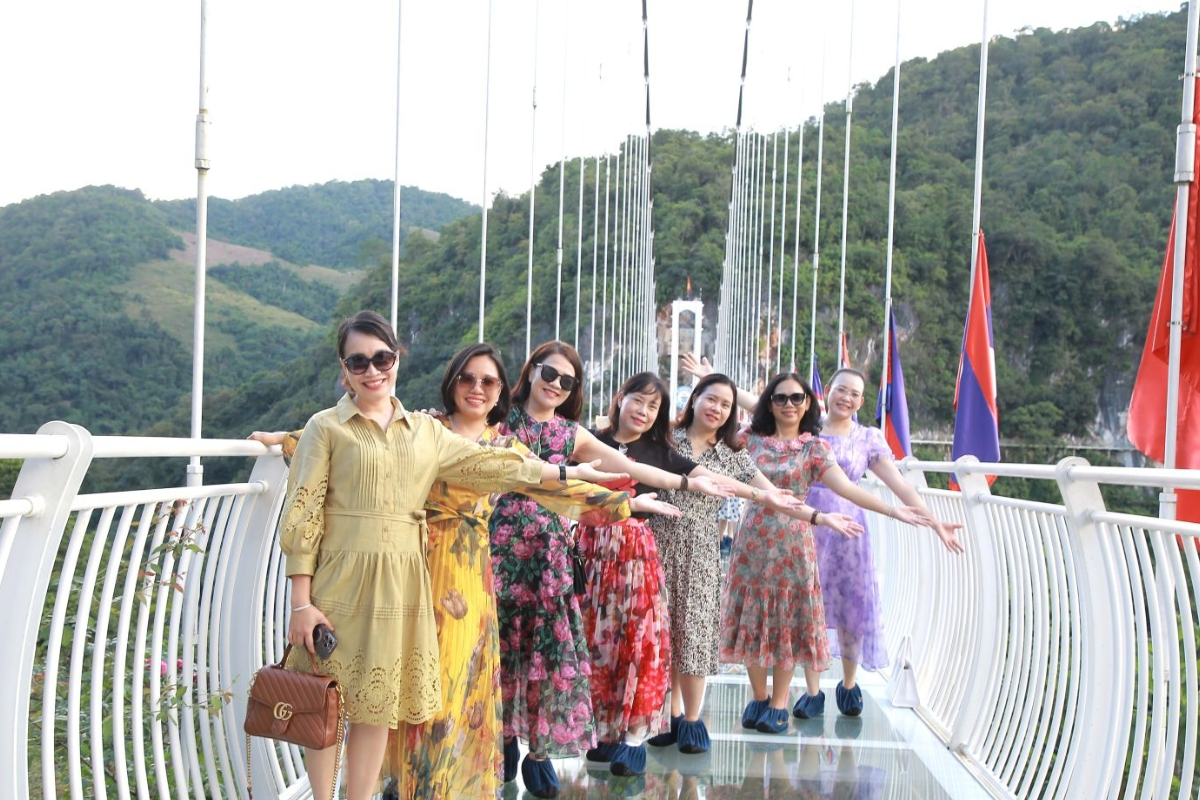 Tourists walking on the transparent Moc Chau Glass Bridge with mountain views