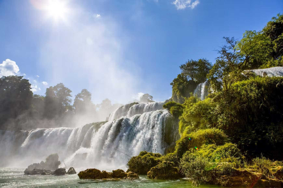 Ban Gioc Waterfall surrounded by lush greenery during a rainy June day