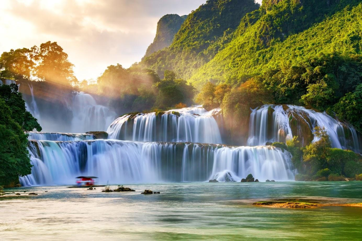Ban Gioc Waterfall in March flowing with strong water over limestone cliffs and surrounded by green hills
