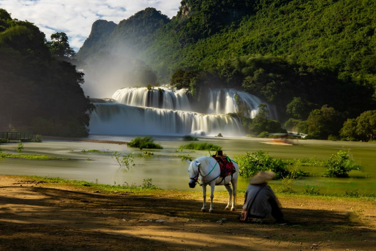 A Person with a horse beside Ban Gioc Waterfall on a calm winter day