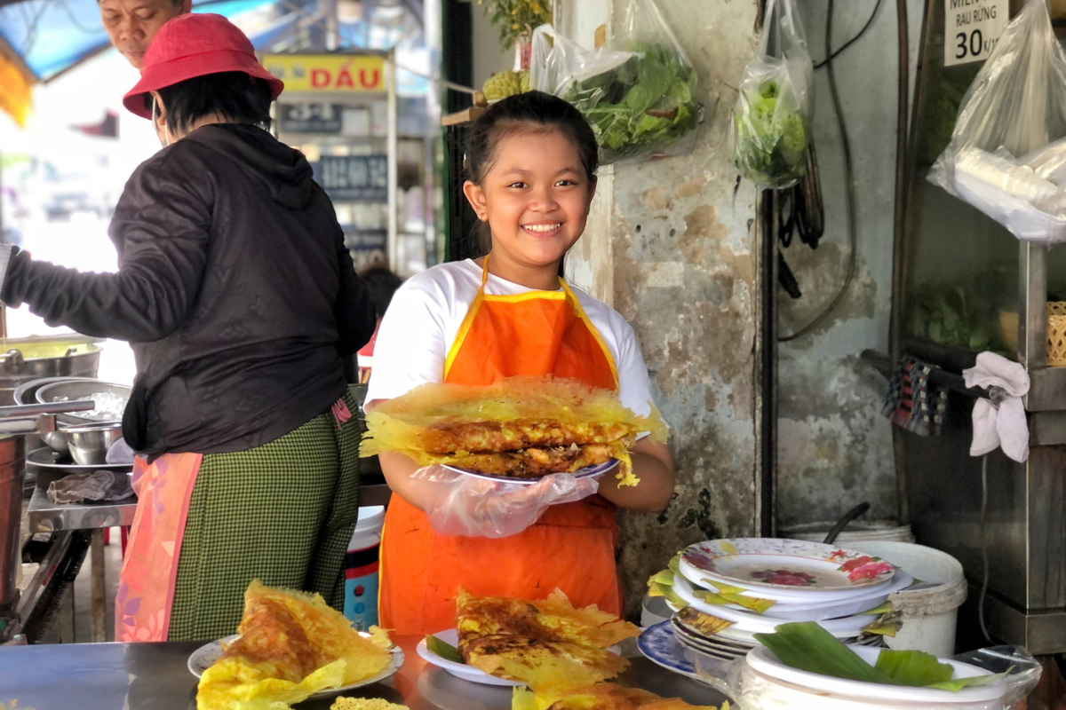 Street food vendor preparing banh xeo in Ho Chi Minh City Street