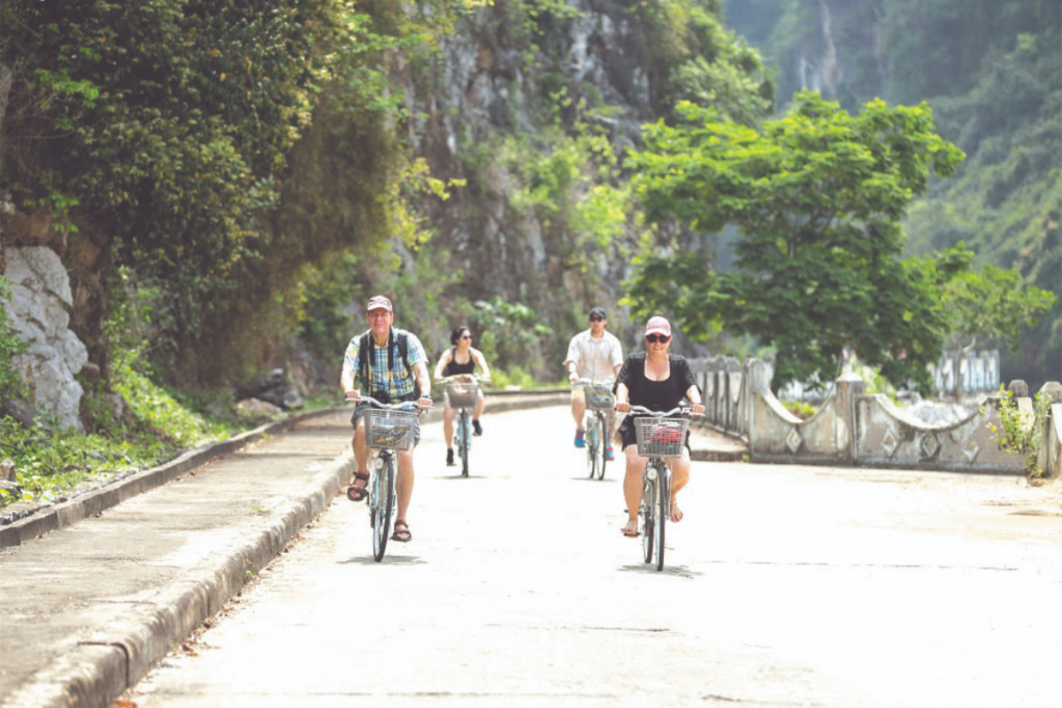Tourist biking through Viet Hai village in lush landscape