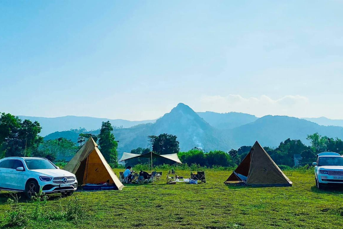 Campers with tents and children playing near Pa Khoang Lake on a sunny day