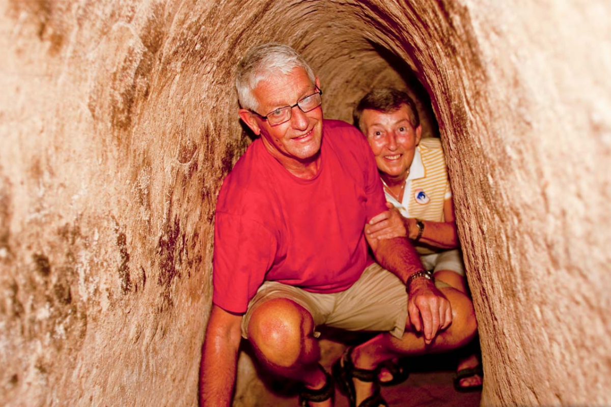 Tourists entering a small tunnel entrance at Cu Chi Tunnels site