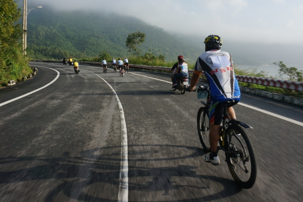 Cyclist on coastal road in Danang with mountain background