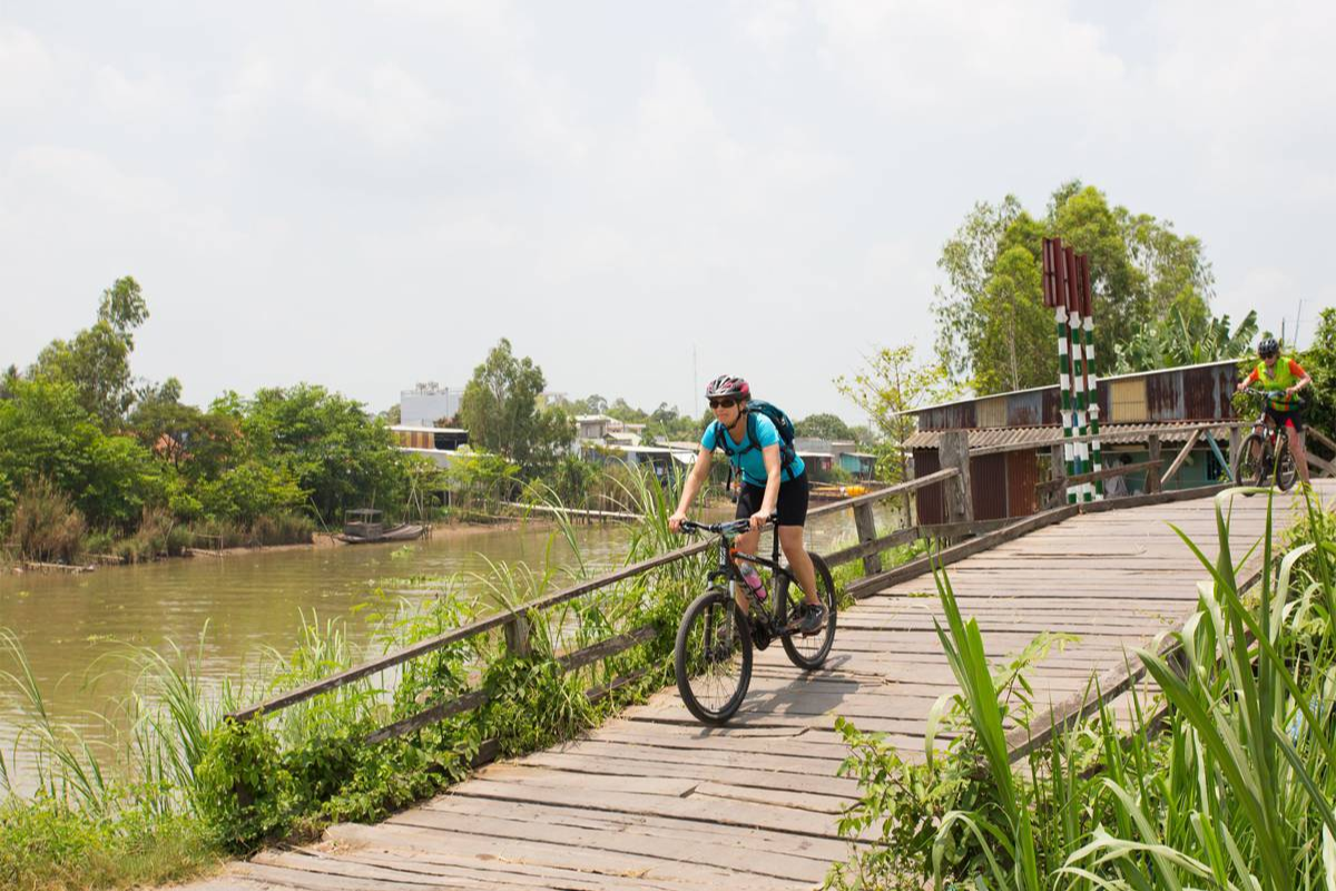 Cyclist riding along canal in the Mekong Delta