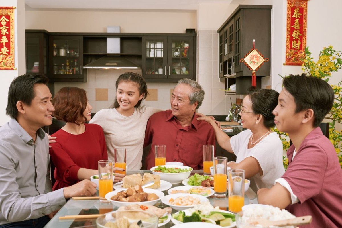 Vietnamese family enjoying Tet dinner with traditional dishes and red decorations