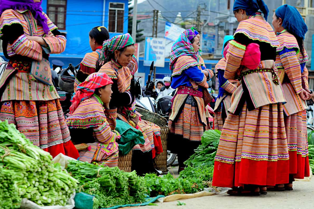 Local H’mong women in traditional dress selling textiles at a Ha Giang market