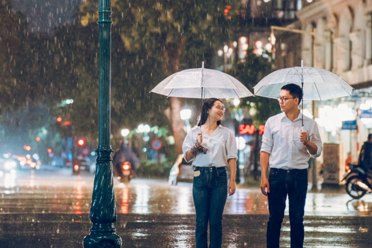 Street in Hanoi with people walking under umbrellas in the rain