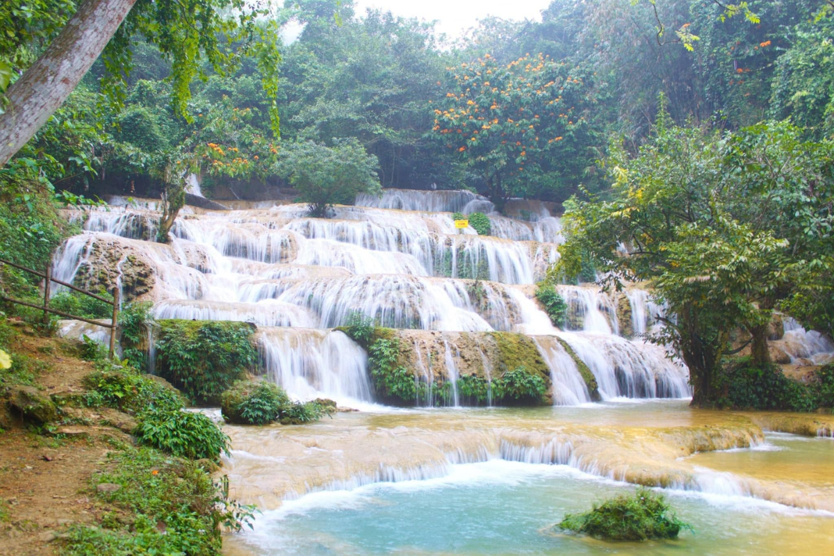 A serene waterfall surrounded by lush greenery in Pu Luong