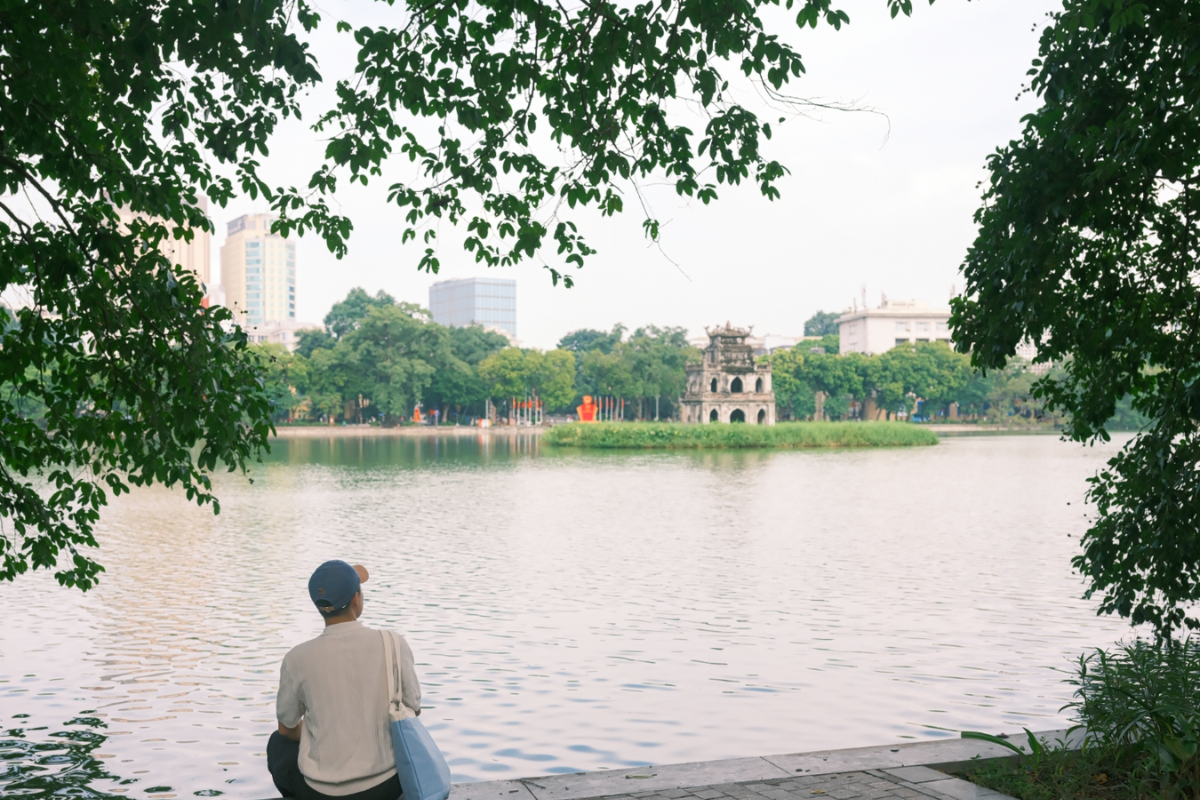 Gentle breeze over Hoan Kiem Lake with people sitting by the shore in Hanoi