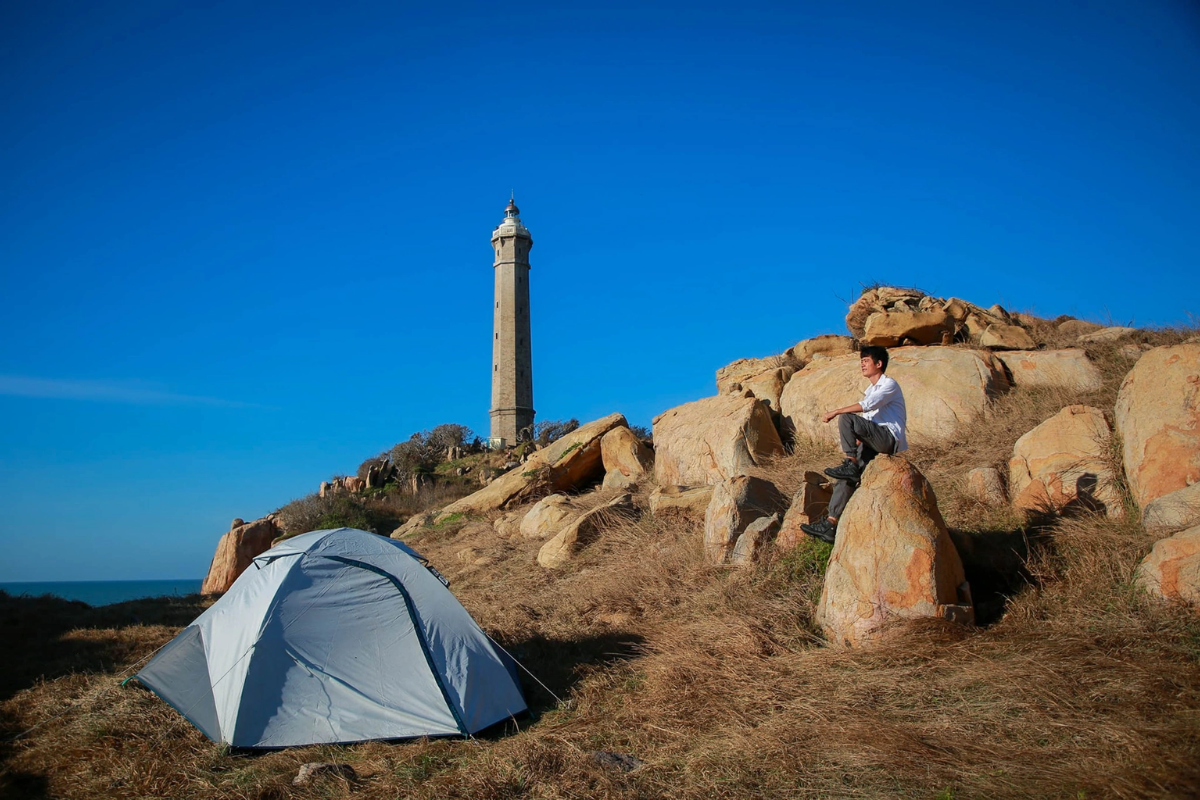 Tent set up near Ke Ga Lighthouse under starry night sky with campfire in the foreground