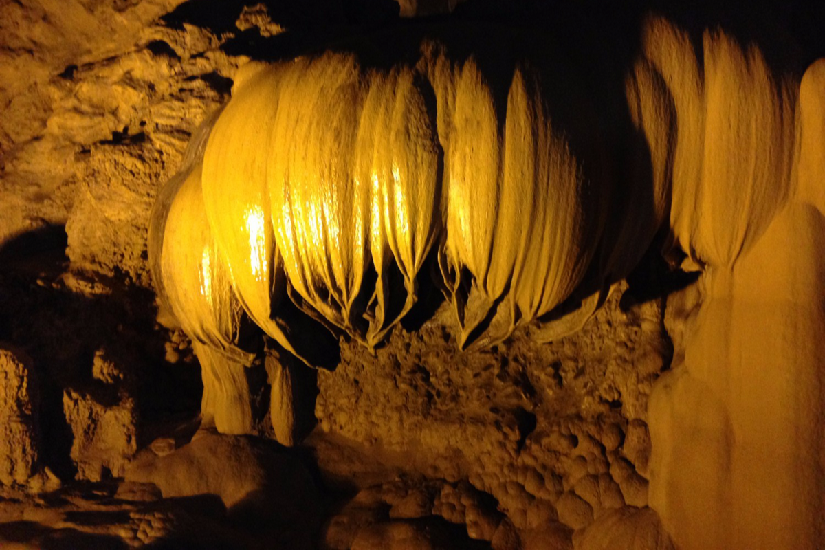 Inside Nguom Ngao Cave with dramatic stalactite formations and ambient lighting