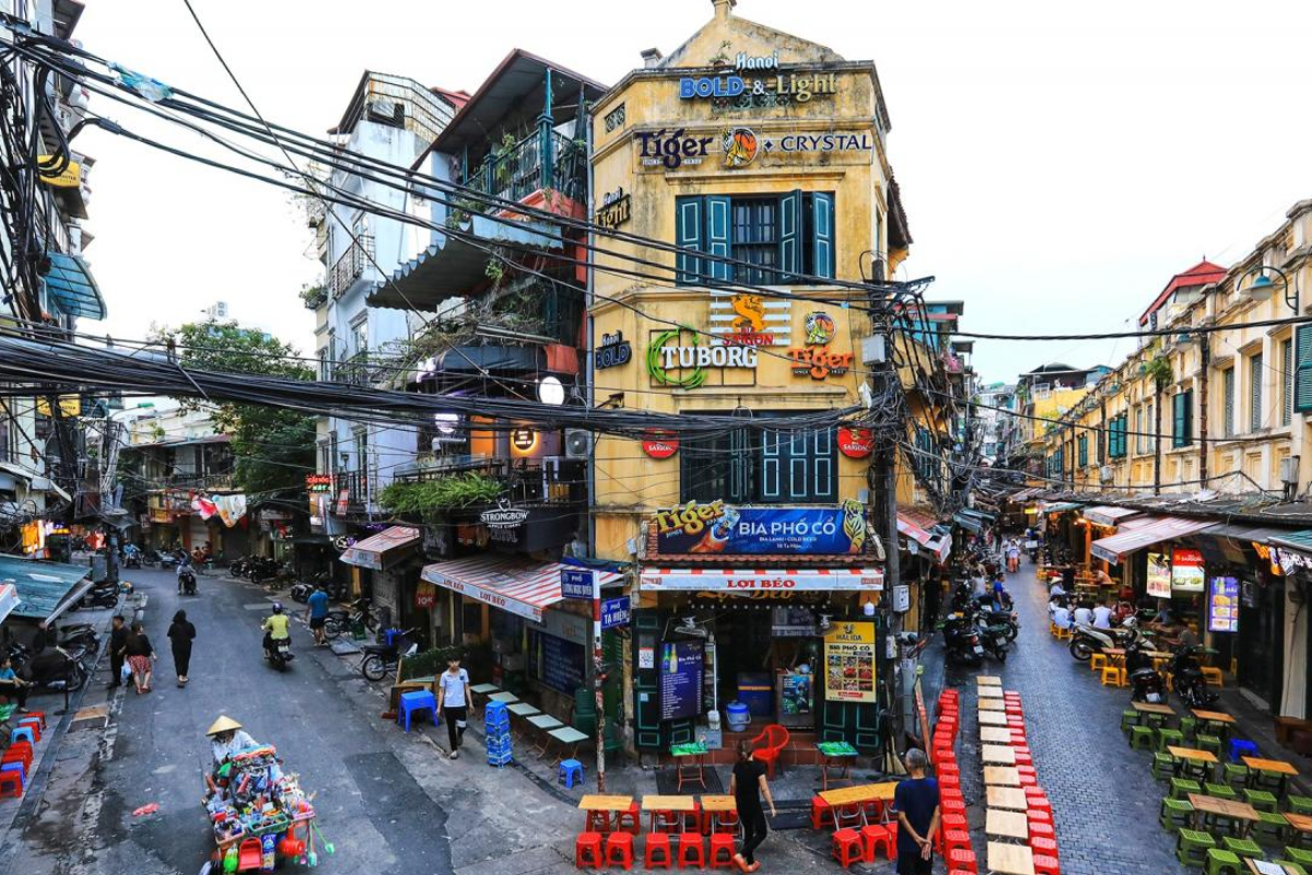 Misty morning in Hanoi's Old Quarter in February with people walking and riding motorbikes