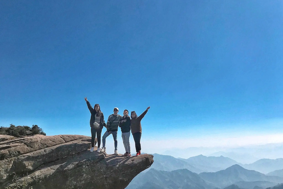 Hiker standing atop Pha Luong Peak with a view of mist-covered valleys