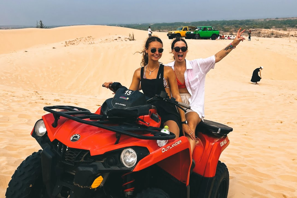 Tourist riding a quad bike on the red sand dunes of Mui Ne at sunset
