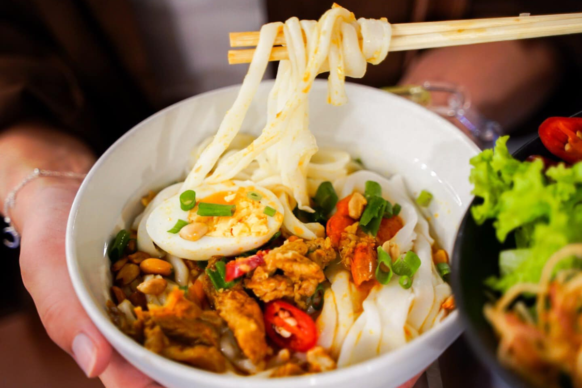 Bowl of Mi Quang with turmeric-flavored noodles, pork, and shrimp