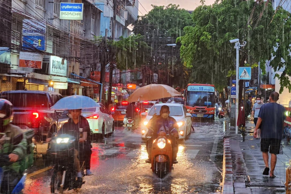 Rainy street in Bangkok during September with people under umbrellas