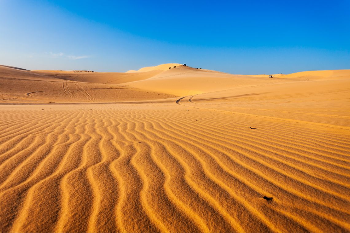 Panoramic view of Red Sand Dunes in Mui Ne, Vietnam at sunset with orange sand hills and tourists