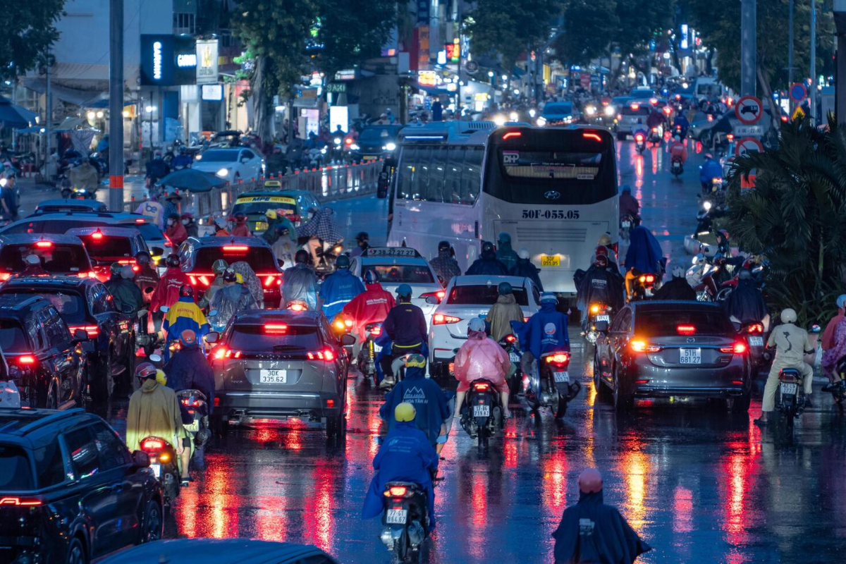 Rainy street scene in Ho Chi Minh City during July with motorbikes and raincoat