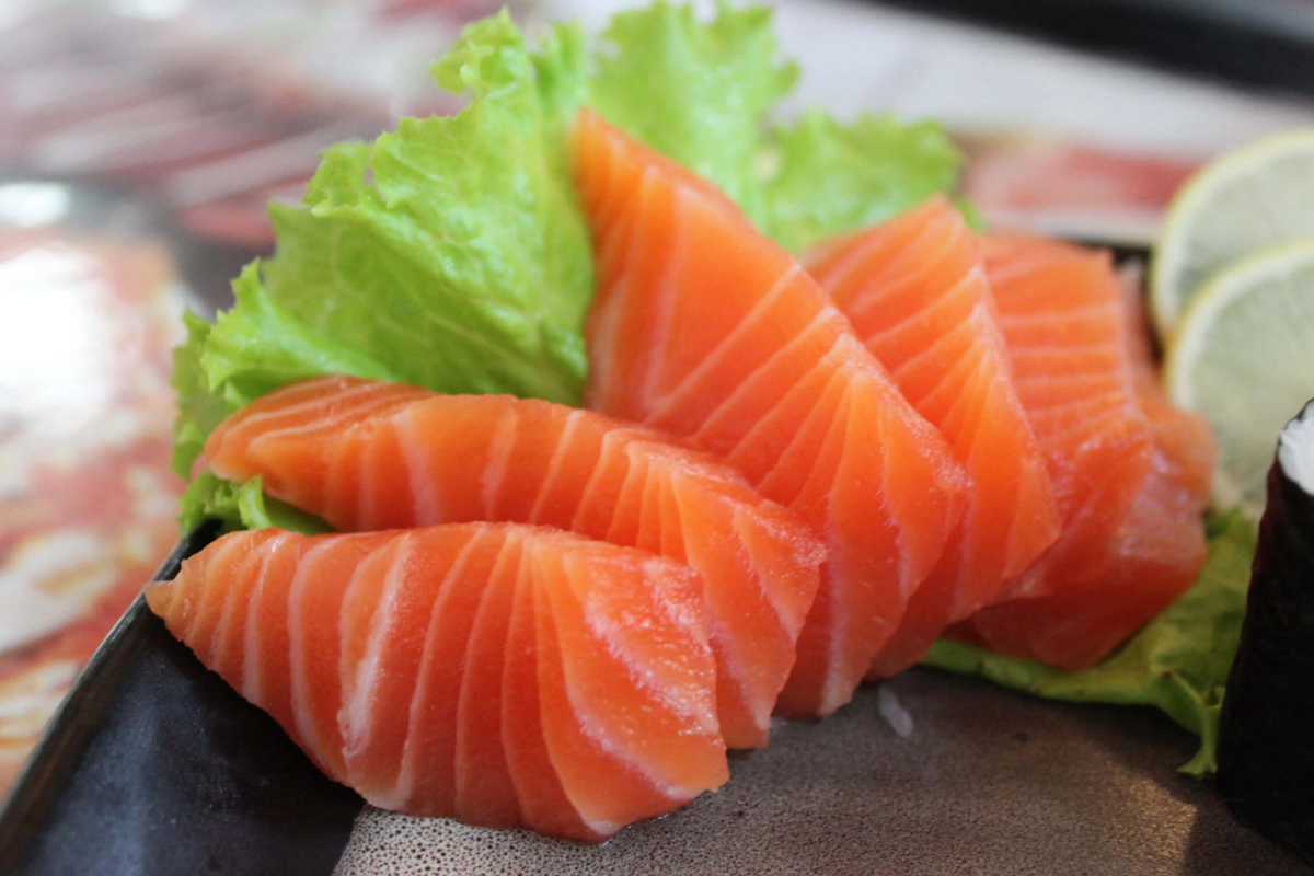 Fresh Moc Chau salmon sashimi served with wasabi, soy sauce, and herbs