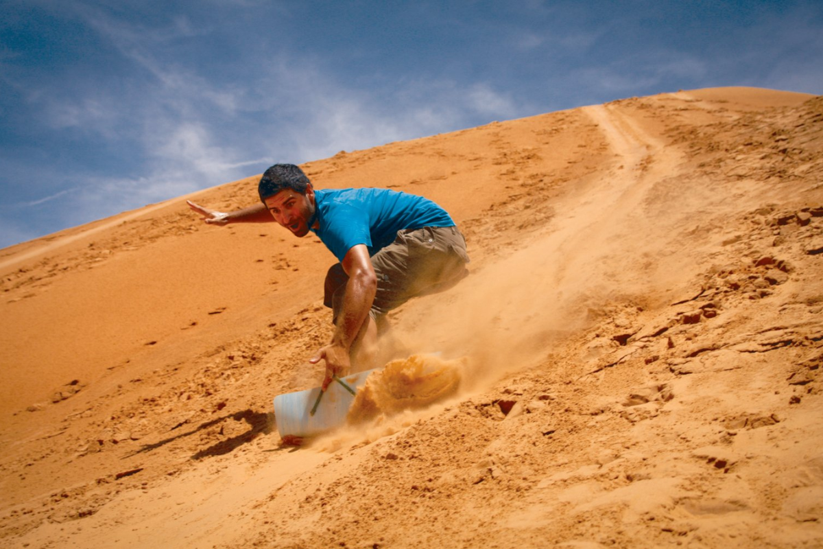 Tourist sandboarding down a dune near Mui Ne