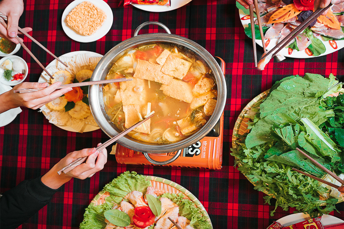 Hot pot meal with mushrooms, herbs, and vegetables in a traditional setting in Sapa