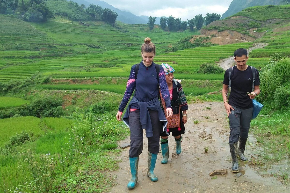 Hiker walking on a trail through the mountains of Sapa with misty hills in the background