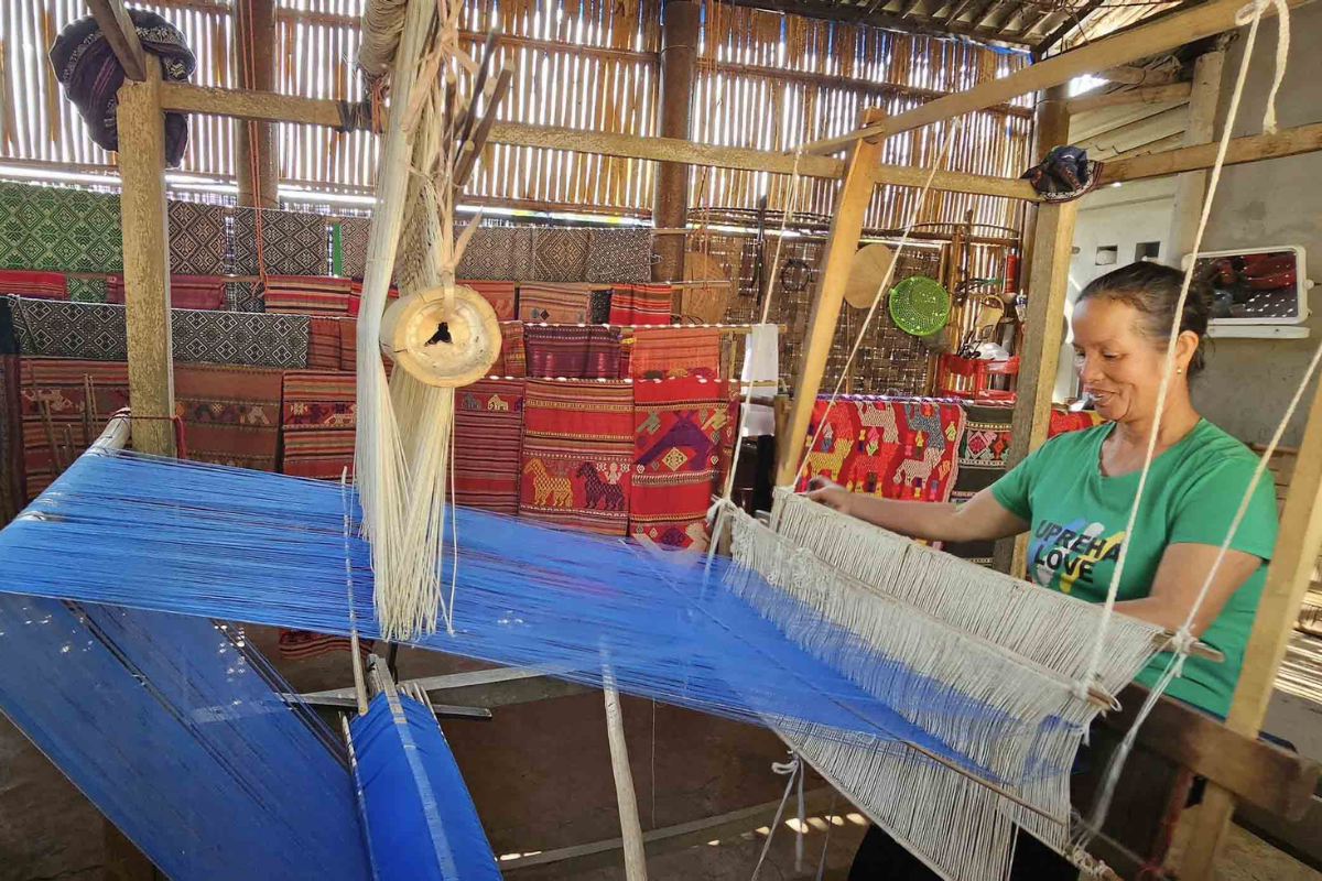 Thai woman weaving traditional textile on a wooden loom in Mai Chau