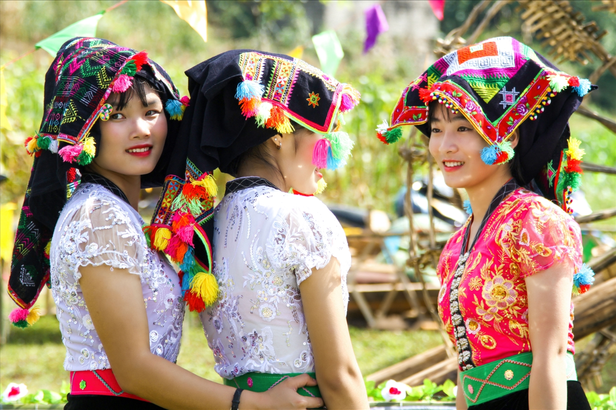 White Thai women in traditional attire smiling and walking in Mai Chau village
