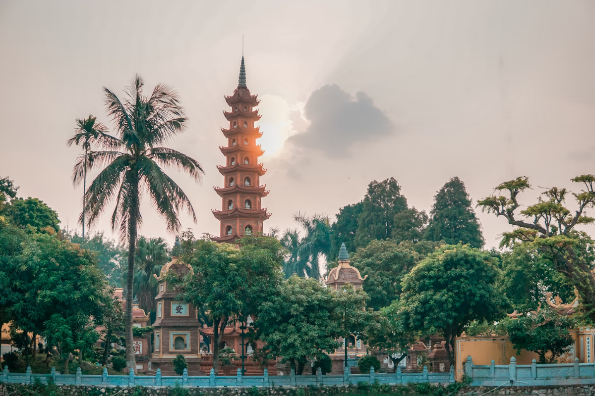 Tran Quoc Pagoda reflecting in West Lake at sunset in Hanoi.