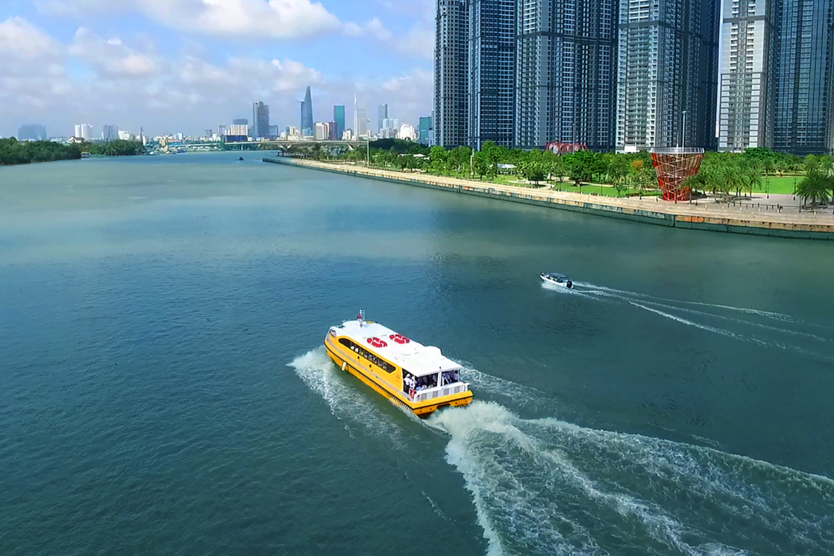 A water bus cruising along the Saigon River with skyline in the background